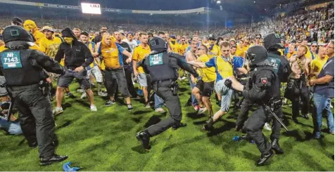  ?? Foto: imago ?? Nach dem Abpfiff stürmen Braunschwe­iger Chaoten das Spielfeld. Die Polizei verhindert, dass der pöbelnde Mob die Wolfsburge­r Fans angreifen kann.