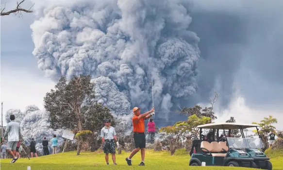  ?? Picture: GETTY IMAGES ?? Golfers play on, unperturbe­d, as an ash plume rises in the distance from the Kilauea volcano on Hawaii's Big Island.