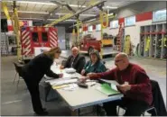  ?? MAUREEN WERTHER ?? Donna O’Neil, left, a Ballston Spa resident for 26years, signs up to vote Tuesday as volunteers Stan DeLong, Donna Duffy and David Beal look on.