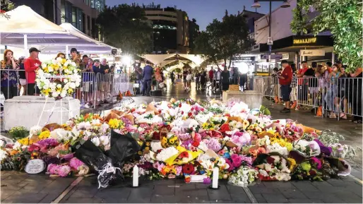  ?? — AFP ?? Members of the public look at flowers placed outside the Westfield Bondi Junction shopping mall in Sydney on Sunday, the day after a 40-year-old knifeman with mental illness roamed the packed shopping centre killing six people and seriously wounding a dozen others.