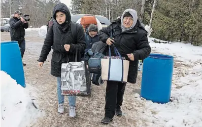  ?? RYAN REMIORZ THE CANADIAN PRESS ?? Asylum seekers from Colombia cross the border at Roxham Road into Canada on Feb. 9, in Champlain, N.Y. Quebec Premier François Legault said “the capacity to receive refugees has been greatly exceeded.”