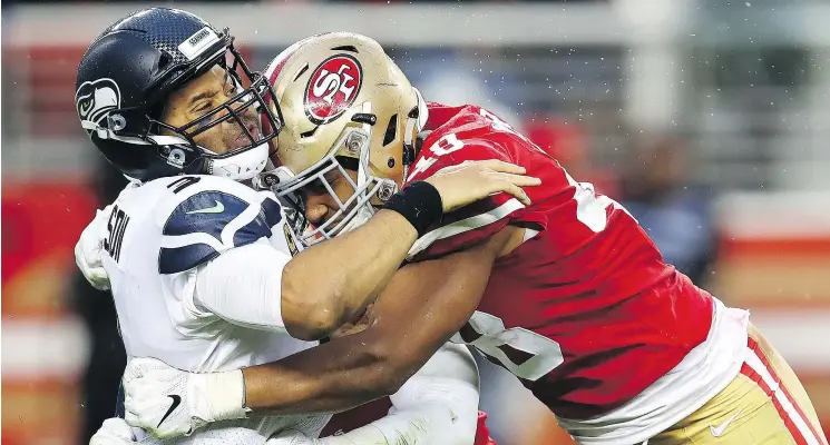  ?? — THE ASSOCIATED PRESS ?? Seahawks QB Russell Wilson takes a big hit from 49ers linebacker Fred Warner on Sunday in Santa Clara, Calif. The 49ers secured a 26-23 OT victory.