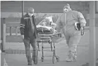  ?? AP ?? Medical workers carry a patient suspected of having coronaviru­s on a stretcher Monday at a hospital in Kommunarka, outside Moscow. Russia’s state coronaviru­s task force reported 29,409 new confirmed cases Monday – the highest number since the start of the year.