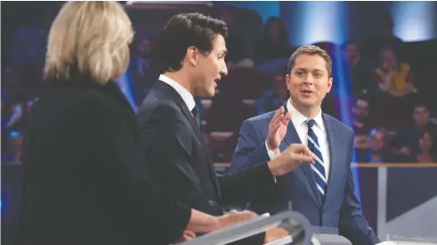  ?? SEAN KILPATRICK / THE CANADIAN PRESS ?? Green Leader Elizabeth May looks on as Conservati­ve Leader Andrew Scheer, right, and Liberal Leader Justin Trudeau debate a point during the federal leaders election debate in Gatineau, Que., on Monday.