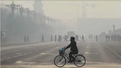 ?? Rodrigo.zeidan@nyu.edu Wang Zhao - 21.dez.2015/AFP ?? Mulher com máscara anda de bicicleta em dia de alerta vermelho contra poluição no centro de Pequim