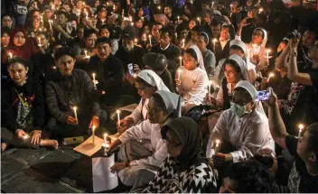  ?? AP FOTO ?? GRIEF. People hold candles during a vigil for the victims of the attacks in Surabaya, Indonesia. A coordinate­d suicide attack carried out by members of the same family struck three churches last Sunday.