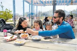  ?? JOSE CARLOS FAJARDO/ STAFF ?? The picnic:
Left: Shelly Ross, of San Francisco, enjoys lunch with her daughters, 4-year-old Emma and toddler Lani, and her husband, Tim Ross, while at the Presidio Tunnel Tops in San Francisco last summer.
Opposite: Children climb and explore the park’s fallen tree playground.