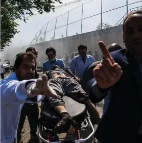  ?? Andrew Quilty / New York Times ?? An injured man is taken to an ambulance near the site of a truck bombing that exploded near the Afghan presidenti­al palace in Kabul in May. The long war in Afghanista­n continues to set records for civilian casualties.