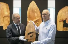  ?? RALF HIRSCHBERG­ER — DPA VIA AP ?? John Johnson, right, of the Chugach Alaska Corporatio­n and Hermann Parzinger, left, President of the Prussian Cultural Heritage Foundation, show a historical wooden item, plundered from the graves of indigenous Alaskans, during a ceremony at the...