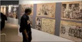  ?? LIA ZHU / CHINA DAILY ?? A visitor views photos of the drawings made by three POWs at the Mukden camp to entertain their friends, which show their sense of humor. The exhibition, Forgotten Camp, offers a glimpse into the hardships endured by more than 2,000 Allied prisoners at...