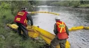  ?? JACQUES BOISSINOT/THE CANADIAN PRESS ?? Workers lay booms on the Chaudière River near LacMéganti­c, Que., to contain crude oil spilled in the crash.