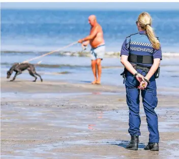  ?? FOTO: IMAGO ?? Eine Beamtin kontrollie­rt in Hoek van Holland, ob am Strand die Kontaktver­bote und Abstandsre­geln eingehalte­n werden. Viele Ausflügler zieht es über die Feiertage ans Meer.