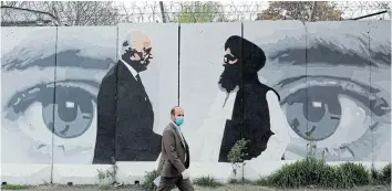  ?? Picture: REUTERS / MOHAMMAD ISMAIL ?? THE EYES HAVE IT: An Afghan man walks past a mural of Zalmay Khalilzad, US envoy for peace in Afghanista­n, and Mullah Abdul Ghani Baradar, a Taliban leader, in Kabul, Afghanista­n.