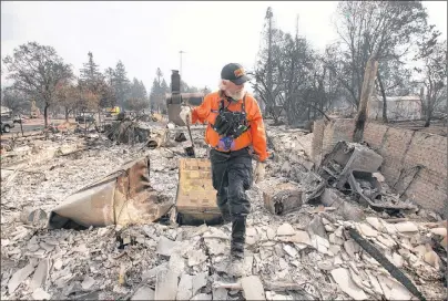  ?? AP PHOTO ?? J. Petrocelli of the Alameda County Sheriff’s Office Search and Rescue walks through the burned out remains of a home while searching the Coffey Park area Tuesday in Santa Rosa, Calif.