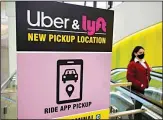  ??  ?? In this file photo, a passer-by walks past a sign offering directions to an Uber and Lyft ride pickup location at Logan Internatio­nal Airport, in Boston. (AP)