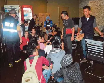  ??  ?? ANGGOTA penguat kuasa menahan warga asing dalam serbuan di sebuah pusat hiburan karaoke di Ampang.
