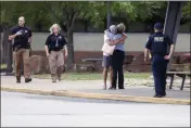  ?? IAN MAULE — TULSA WORLD ?? Two people hug outside at Memorial High School in Tusla, Okla., where people were evacuated from the scene of a shooting at the Natalie Medical Building on Wednesday.