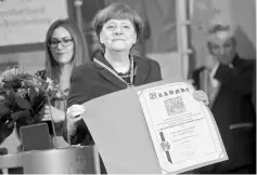  ??  ?? Merkel holds a certificat­e during a reception of German carnival societies at the Chanceller­y in Berlin, Germany. — Reuters photo
