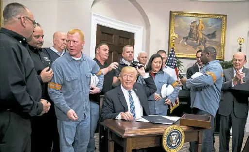  ?? Doug Mills/The New York Times ?? President Donald Trump, joined by steelworke­rs, hands out pens he used to sign an order imposing sweeping new tariffs on steel and aluminum Thursday at the White House. Mr. Trump’s orders will raise levies on steel by 25 percent and aluminum by 10 percent.