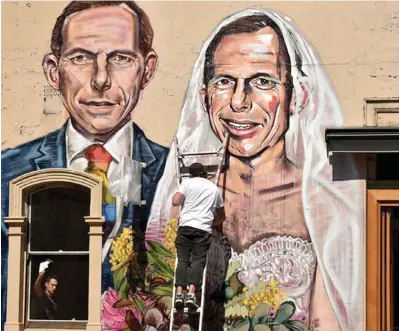  ??  ?? Australian street artist Scottie Marsh paints a mural of former Australian Prime Minister Tony Abbott wedding himself in Sydney after Mr Abbott urged Australian­s to “protect the family” with their vote in the same-sex marriage postal survey.