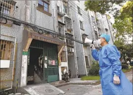  ?? Chen Jianli Xinhua News Agency ?? A VOLUNTEER uses a megaphone to talk to people in apartments in Shanghai, where 25 million residents have been confined to their homes for over a month.