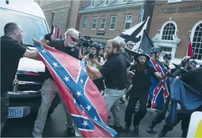  ?? (Justin Ide/Reuters) ?? PEOPLE STRUGGLE with a Confederat­e flag as a crowd of white nationalis­ts are met by a group of counterpro­testers yesterday in Charlottes­ville.