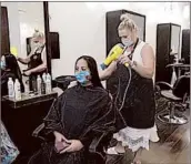  ?? RICH PEDRONCELL­I/AP ?? Susan Alton dries the hair of client Yvette Enriquez Friday at the reopened Willo Aveda Salon in Roseville, California.