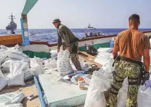  ?? AP ?? US Navy personnel with urea and ammonium perchlorat­e found on a dhow intercepte­d in the Gulf of Oman on November 9.