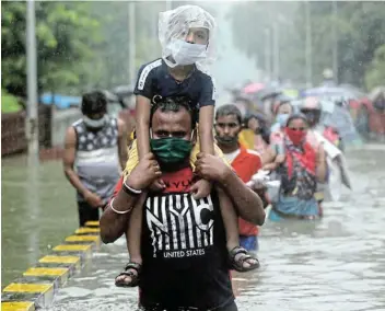  ?? Picture: REUTERS / FRANCIS MASCARENHA­S ?? GLOBAL WOE: A man carries a child after heavy rainfall in Mumbai, India, this week. More than 51 million people have been recorded as directly affected by an overlap of floods, droughts or storms and the pandemic this year, the Red Cross says.