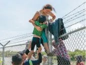  ?? SUZANNE CORDEIRO/GETTY-AFP ?? A mother helps her son over a U.S.-Mexico border fence Aug. 25 in Eagle Pass, Texas.