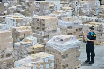  ?? Los Angeles County ?? DANIELLE McMILLON, a lifeguard with the Los Angeles County Fire Department, surveys a stockpile of surgical and protective masks stored in a secret government warehouse and destined for area hospitals.