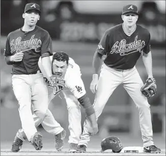  ?? Wally Skalij Los Angeles Times ?? ADRIAN GONZALEZ of the Dodgers tries to retrieve his helmet between Andrelton Simmons, left, and Elliot Johnson of the Atlanta Braves in the third inning.