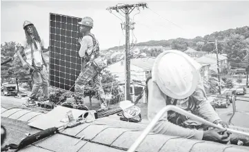  ??  ?? Rawlings, left, Dominic Paul-Baha, centre, and Antwain Nelson, right, work on a solar panel installati­on on the roof of Catherine Bennett’s home in Washington Friday July 28