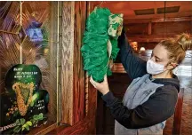  ?? BILL LACKEY / STAFF ?? Kadie Cordle, an employee at O’Conner’s Irish Pub, decorates for the holiday Monday.