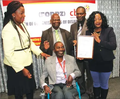  ?? Picture by John Manzongo ?? Zimpapers Group public relations and corporate affairs manager Ms Beatrice Tonhodzayi (right) receiving an award from Federation of Disabled persons in Zimbabwe chairperso­n Mr Watson Khupe (seated) in Harare yesterday for the group’s efforts in...