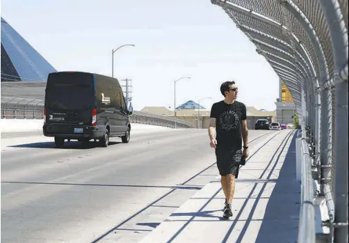  ?? STEVE MARCUS ?? Las Vegas Sun reporter Adam Candee walks a week ago on the Hacienda Avenue bridge over I-15, during a walk from the Strip to the site of the stadium where the Raiders will play when they move to Las Vegas.