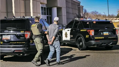  ?? GABRIELA CAMPOS/NEW MEXICAN FILE PHOTO ?? Deputy Jeffrey Naas with the Bernalillo County Sheriff’s Office walks a suspect to the back of a squad car in February after the man was arrested on suspicion of shopliftin­g at a Kohl’s in Albuquerqu­e. Local chambers of commerce officials say the state’s efforts on organized retail crime are having an impact.