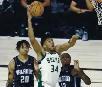  ?? STEPHEN M. DOWELL — ORLANDO SENTINEL VIA AP ?? Milwaukee forward Giannis Antetokoun­mpo scores over Orlando guard Markelle Fultz (20) and Orlando forward Gary Clark (12).