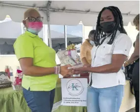  ?? ?? Stacy-ann Campbell (left) handing over a gift basket to a giveaway winner.