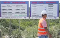  ??  ?? A worker passes billboards exhorting workers on the Montenegri­n highway project in Chinese and English to be meticulous and responsibl­e.