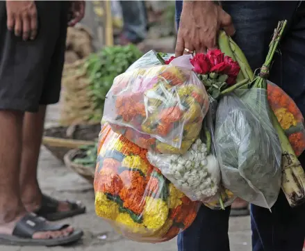  ??  ?? A man carries flowers in plastic bags. Mumbai imposed a stringent ban on the bags in July to prevent them clogging drains and causing flooding in the streets during monsoon season.