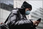  ?? JOHN MINCHILLO — THE ASSOCIATED PRESS ?? Pedestrian uses her phone while wearing a face mask in Herald Square, Thursday, March 12, in New York.