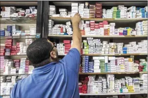  ?? KHALED DESOUKI/AFP ?? An Egyptian pharmacy employee reaches out to grab a box of medicine in a pharmacy in the capital Cairo on November 9.