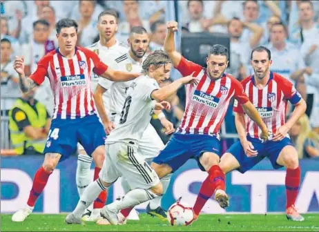  ??  ?? Real Madrid's Luka Modric (C) finds his route barred by Atletico players during their La Liga clash at the Santiago Bernabeu Stadium on Saturday.