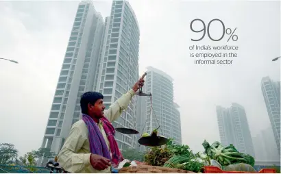  ?? AFP ?? a vendor weighs vegetables alongside high-rise buildings in Kolkata. Informal workers are the newly emerging home-owning class. —