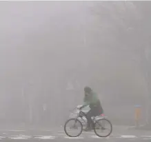  ?? Yonhap ?? A bike rider crosses a road amid dense fine dust in Gwangju, Monday.