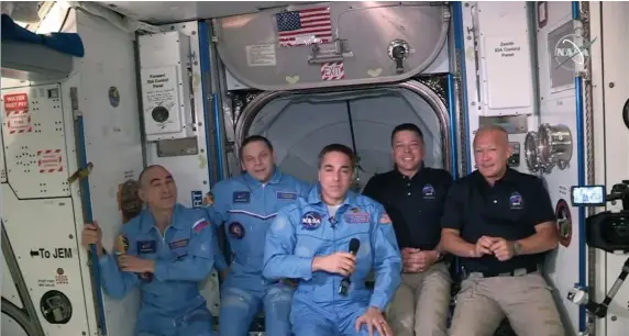  ?? getty IMages ?? ALL TOGETHER NOW: In this screen grab from NASA's feed, NASA astronauts Doug Hurley, right, and Bob Behnken, second from right, join NASA astronaut Chris Cassidy, center, and Russian cosmonauts, Anatoly Ivanishin, left, and Ivan Vagner, second from left, aboard the Internatio­nal Space Station after successful­ly docking SpaceX's Dragon capsule Sunday.