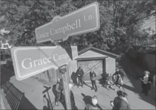  ?? SCOTT GARDNER, THE HAMILTON SPECTATOR ?? People gather beneath signs marking Grace Campbell Lane after a community ceremony Saturday morning off Gibson Avenue. The city named the laneway after Grace Campbell who died in August. Campbell was a tireless volunteer in her community.