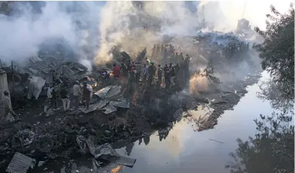  ?? Picture: AFP ?? LIVES IN RUINS. Debris smoulders after a fire gutted a timber dealership at Gikomba market and spread to nearby stalls and homes in Nairobi yesterday. Nine of the dead were in flats next to the market.