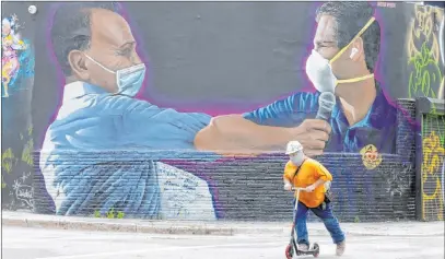  ?? Wilfredo Lee The Associated Press ?? A constructi­on worker rides a scooter Monday past a mural of billionair­e businessma­n Moishe Mana, left, and Miami Mayor Francis X. Suarez. Florida surpassed its previous one-day record for coronaviru­s deaths Tuesday, reporting 132 additional deaths.